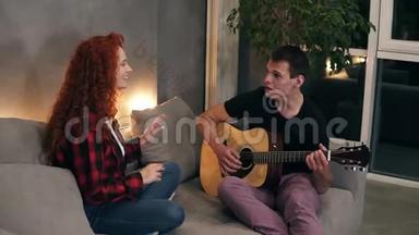 一位丈夫正在为他的妻子唱一首歌，弹一把吉他，妻子也和他一起坐在沙发上唱歌